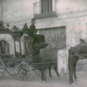 Un cochero espera en el coche fúnebre tirado por caballos