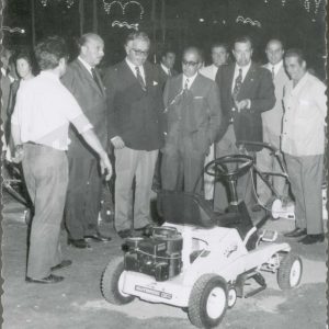 El Alcalde de Aranjuez, Antonio Clavet, junto a otras personas observando un cortacesped motorizado en la Feria de Muestras durante las Fiestas de Aranjuez