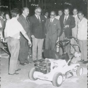 El Alcalde de Aranjuez, Antonio Clavet, junto a otras personas observando un cortacesped motorizado en la Feria de Muestras durante las Fiestas de Aranjuez