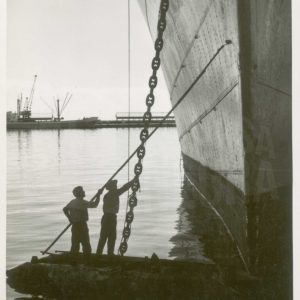 Dos trabajadores limpiando el casco de un barco de grandes dimensiones en el Puerto de Alicante