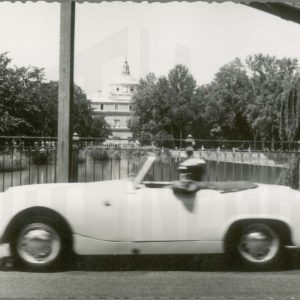 Un coche descapotable atraviesa el Puente de Barcas con el río Tajo y el Palacio Real al fondo