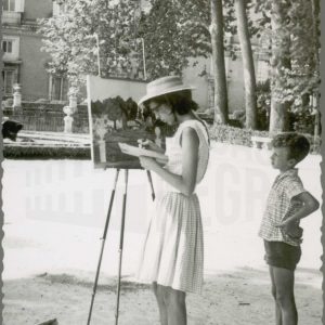 Un niño observa a una pintora en el Jardín de la Isla de Aranjuez, con el Palacio Real al fondo