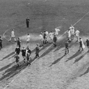 Centro de un campo de futbol con los jugadores y árbitros en el terreno de juego