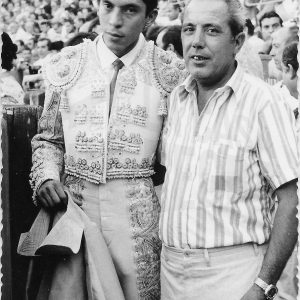 Señor posando con un torero en una plaza de toros