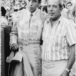 Señor posando con un torero en una plaza de toros