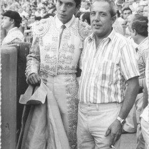 Señor posando con un torero en una plaza de toros