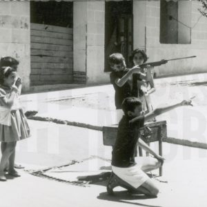 Niños y niñas en la calle con una escopeta de aire comprimido
