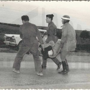 Un guardia civil y otras personas trasladan a un herido en un accidente de tráfico