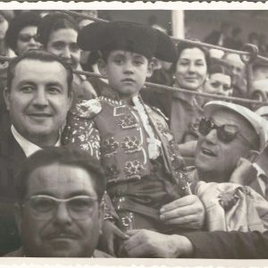 Niño con traje de luces, junto a varios locutores de Radio Madrid, en el tendido de la plaza de toros de Aranjuez durante la Feria de San Fernando.