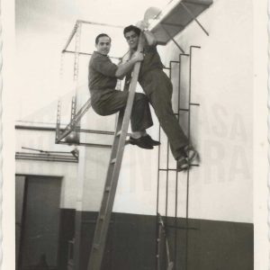 Dos personas en una escalera de mano en la factoría de MAFE (Manufacturas Fotográficas Españolas) en Aranjuez