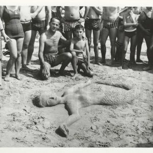 Padre e hijo posando ante una escultura de arena en la playa.