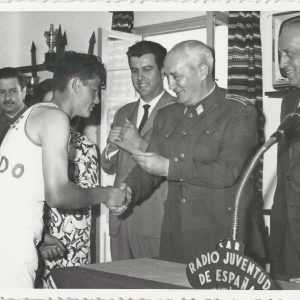 Un deportista es saludado por un general de brigada ante un micrófono de Radio Juventud de España