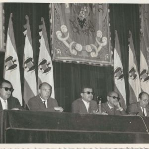 Cinco señores en un estrado en un acto político