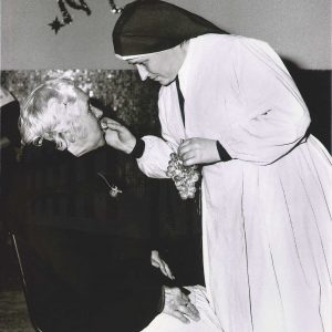 Una monja da de comer las uvas de Nochevieja a una señora mayor en el Asilo de San Isidro en Aranjuez