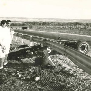 Coche de carreras accidentado y tres hombres a su lado