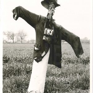 Espantapájaros con cámara de fotos en un campo