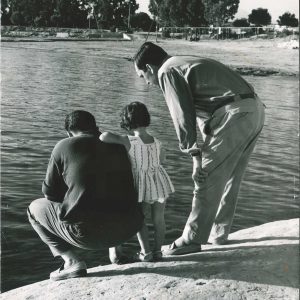 Dos hombres y una niña en la orilla de un lago