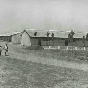 Dos niños pasean de la mano junto a barracones utilizados como viviendas provisionales en Aranjuez