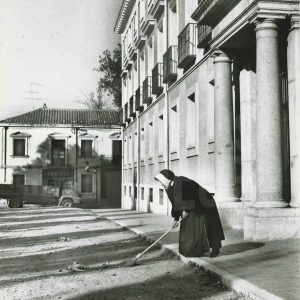 Una monja barriendo en la puerta del Colegio Sagrada Familia de Aranjuez