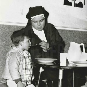 Una monja dando de comer a un niño pequeño en una guardería de Caridad en Aranjuez