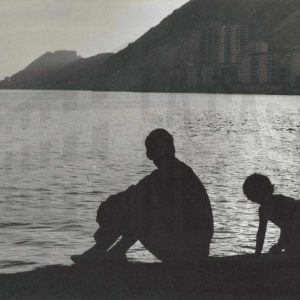 Perfiles de un hombre y una niña a contraluz frente al mar en la costa de Alicante