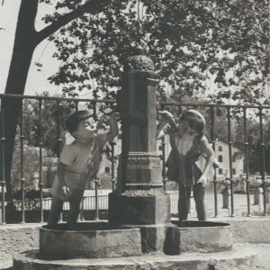 Un niño y una niña beben agua de una fuente en Aranjuez
