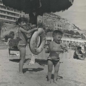 Un niño llorando y una niña bajo una sombrilla en una playa