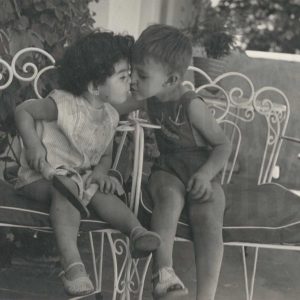 Un niño y una niña sentados en sillas de jardín se dan un beso