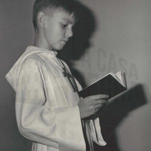 Un niño vestido de Primera Comunión lee un libro