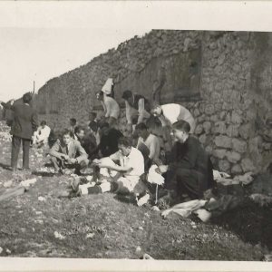 Grupo de hombres calzandose las botas junto a una tapia