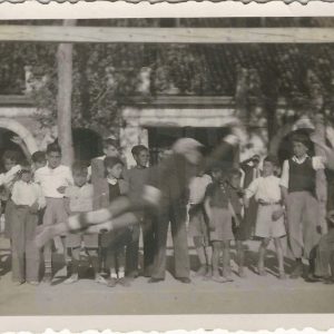 El portero intenta detener el balón en el Campo de Fútbol de las Cuerdas en la Plaza de Parejas de Aranjuez. Niños observan la jugada. Detrás la Casa de Oficios