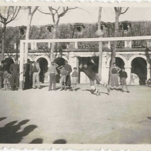 Portero intentando atrapar el balón en el Campo de Fútbol de las Cuerdas de la Plaza de Parejas de Aranjuez. Al fondo la Casa de Oficios