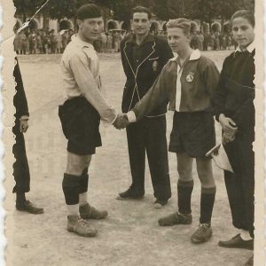 Capitanes de ambos equipos se saludan antes del partido flanqueados por el árbitro y los linieres en el Campo de Fútbol de las Cuerdas en la Plaza de Parejas de Aranjuez. Al fondo  la Casa de Oficios