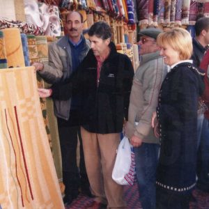 Vendedor de alfombras mostrando su mercancía a clientes en el Rastro de Aranjuez