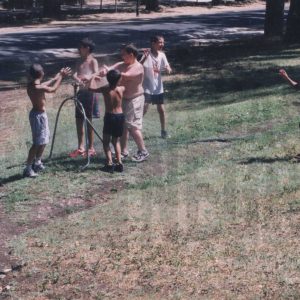 Niños refrescándose con el agua de un aspersor en la Calle de la Reina de Aranjuez
