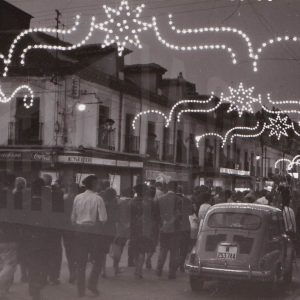 Numerosas personas caminando por la calle Stuart de Aranjuez de noche con iluminación de fiestas