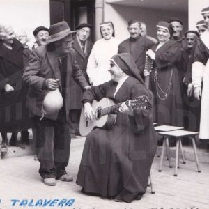 Un monja toca la guitarra con otras monjas y personas mayores a su alrededor en el asilo de San Isidro de Aranjuez