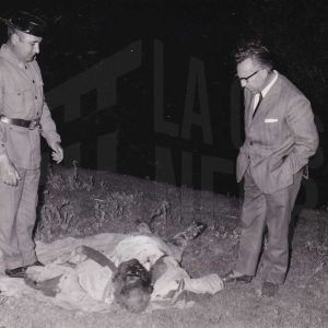 Un guardia civil y otro señor contemplan el cadaver de un hombre en la orilla del río Tajo en Aranjuez