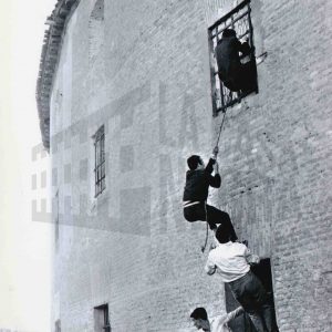 Varias personas trepando con una cuerda por la fachada de la Plaza de Toros de Aranjuez para colarse en un espectáculo