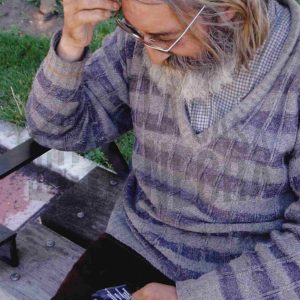 Un señor lee un folleto sentado en un banco en Aranjuez