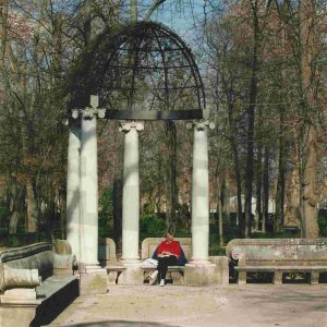 Una visitante sentada en uno de los bancos de las exedras de la Fuente de las Harpías O del Niño de la Espina) en el Jardín de la Isla en Aranjuez