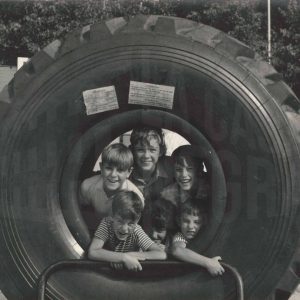 Los primos Gálvez, hijos y sobrinos del fotógrafo, se asoman por el agujero de un gran neumático en la Feria de Muestras de Aranjuez