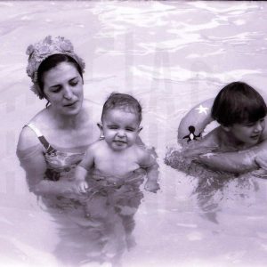 Una mujer en la piscina con un niño y un bebé