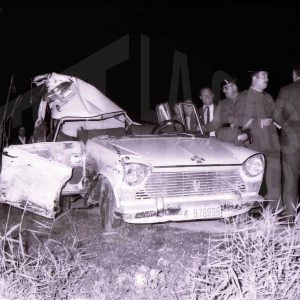 Dos guardias civiles y otras personas junto a un coche accidentado en una carretera