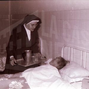 Monja atendiendo a anciana yacente en el Asilo de San Isidro en Aranjuez