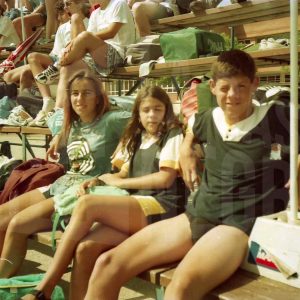 Dos niñas y un niño en las gradas de una piscina