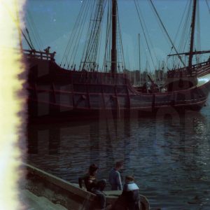 Tres niños frente a la reproducción de la Nao Santa María en el puerto de Barcelona