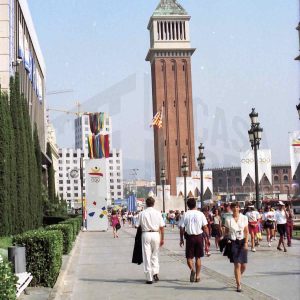 Varias personas caminando por la Avenida de la Reina María Cristina de Barcelona con las Torres Venecianas al fondo