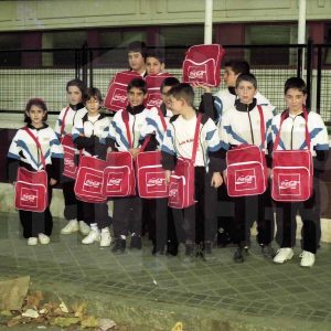Un grupo de niños y niñas con bandoleras de Coca Cola