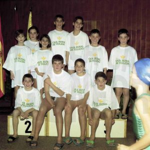 Un grupo de nadadores y nadadoras sobre un podio con camisetas de Caja Rural de Toledo
